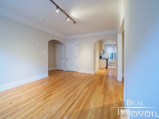 A spacious room with wooden flooring and white walls.