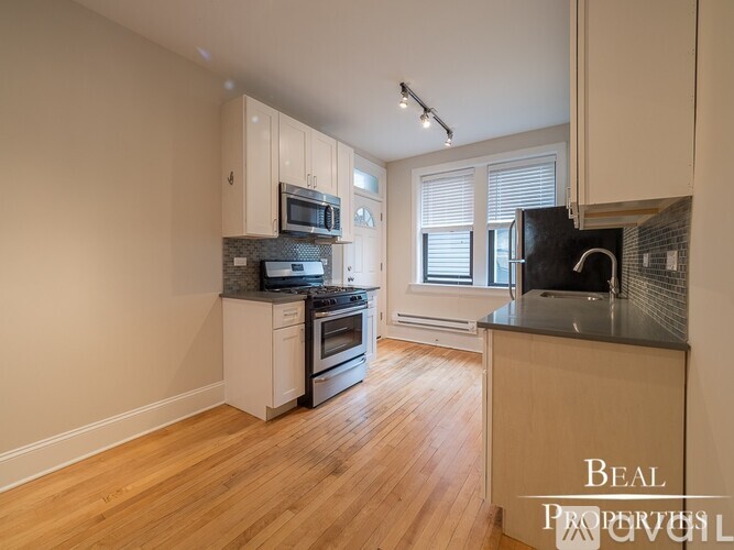 A kitchen with wooden floors and a countertop with a microwave and oven.