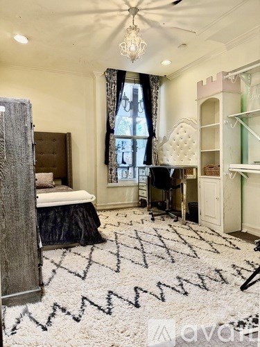 A bedroom with a large bed, a desk, and a ceiling fan.