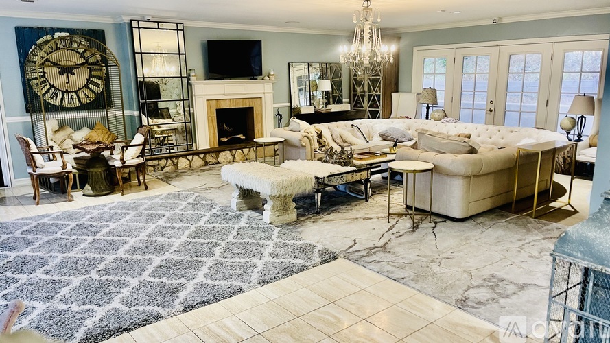 A large, well-furnished living room with a fireplace and a large clock on the wall.