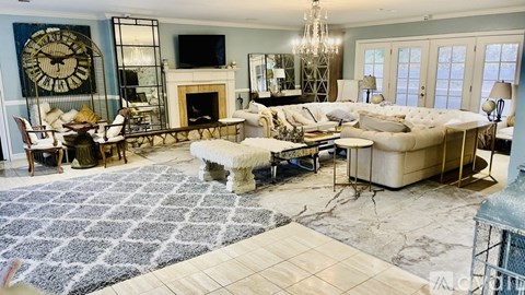A large, well-furnished living room with a fireplace and a large clock on the wall.