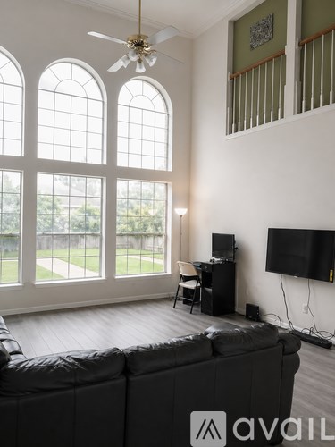 A living room with a black couch and a television on the wall.