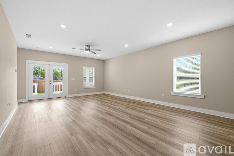 A spacious room with wooden flooring and a ceiling fan.