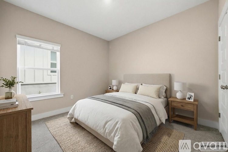 A bedroom with a bed, nightstand, and window.