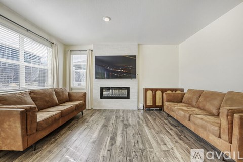 A living room with two brown couches and a fireplace.
