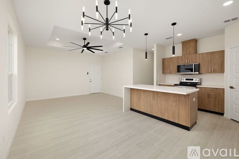 A spacious kitchen with a ceiling fan and a microwave on the counter.