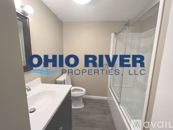 A bathroom with a toilet, sink, and shower with a sign that says Ohio River Properties, LLC.