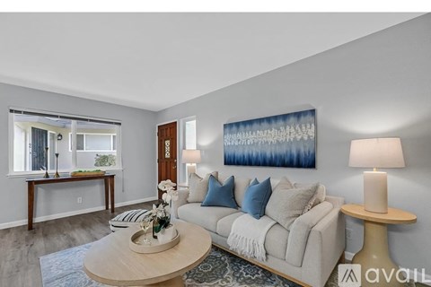 A living room with a couch, a coffee table, and a painting on the wall.