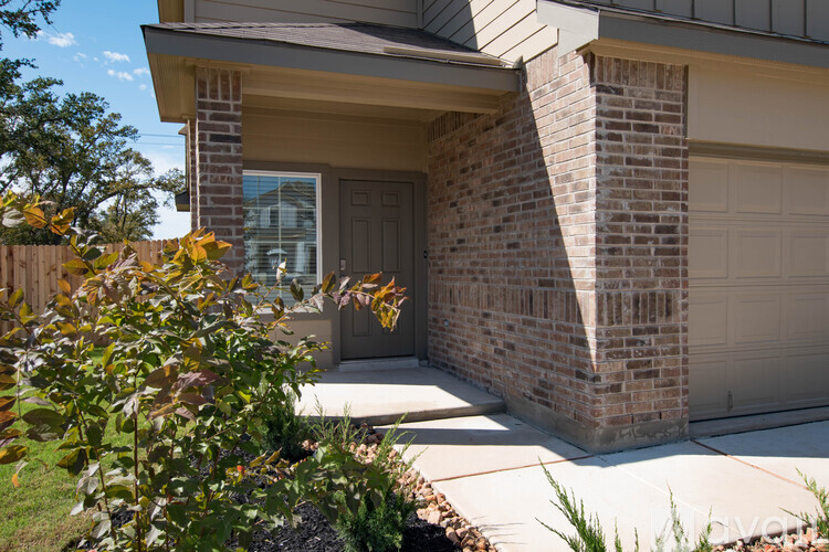 A house with a brown brick wall and a grey garage door.