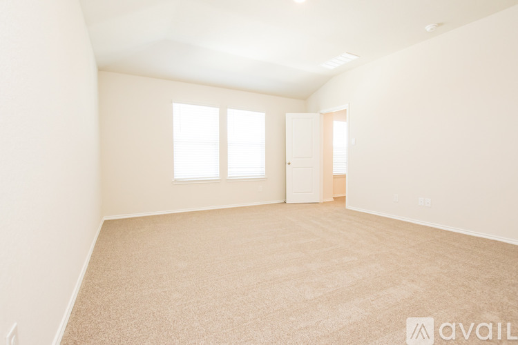 A spacious room with carpeted floor and two windows.