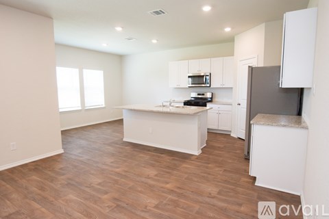 A kitchen with white cabinets and a wooden floor.