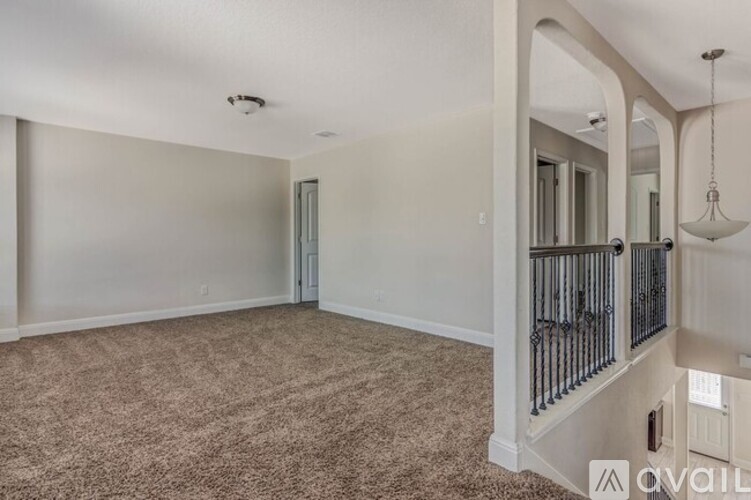 A spacious living room with a carpeted floor and a balcony with a railing.
