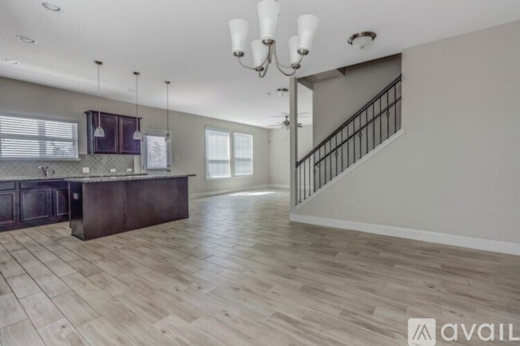 A spacious kitchen with a dark wood island and pendant lights.