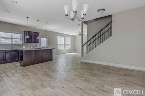 A spacious kitchen with a dark wood island and pendant lights.