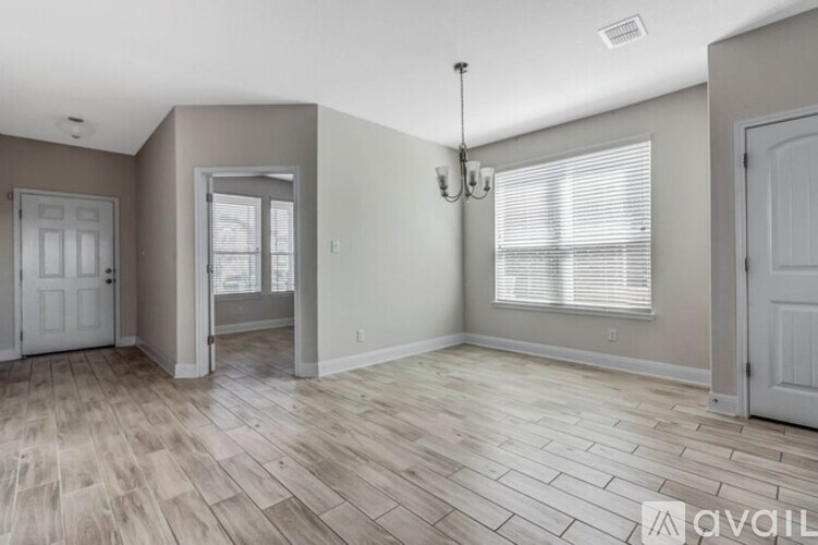 A spacious room with wooden flooring and a chandelier.