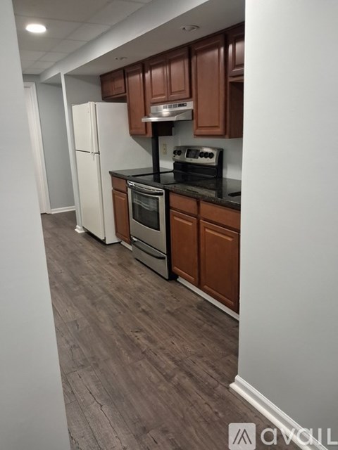A kitchen with brown cabinets and a black countertop.