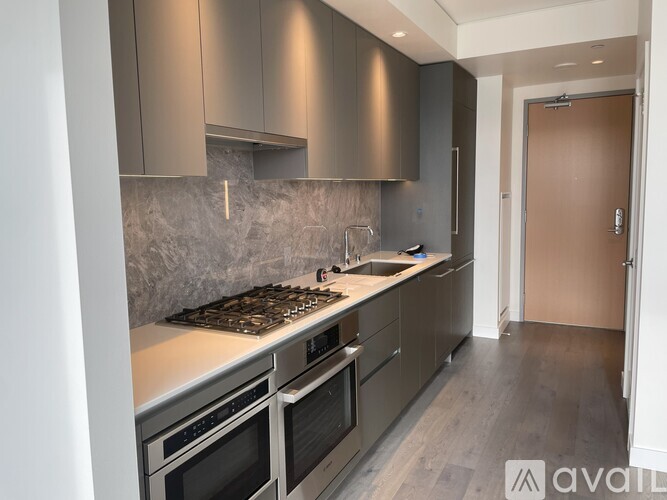 A modern kitchen with stainless steel appliances and a marble backsplash.