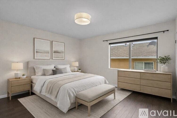 A bedroom with a large bed, two nightstands, and a window with a view of a building.