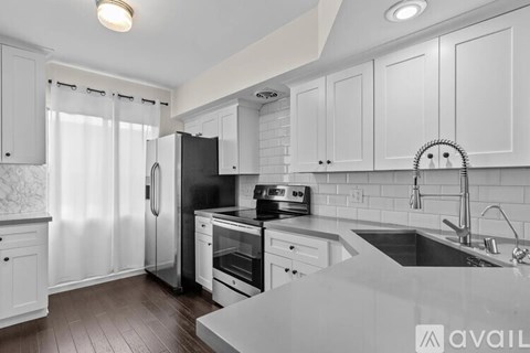 A kitchen with white cabinets and a black refrigerator.