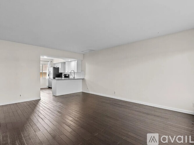 A spacious room with wooden flooring and white walls.
