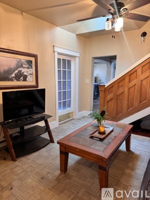 A living room with a television, a coffee table, and a painting on the wall.