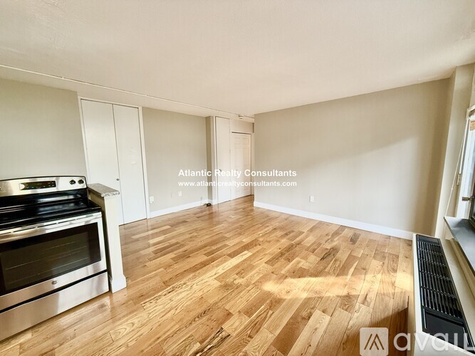 A spacious room with wooden flooring and a stainless steel oven.