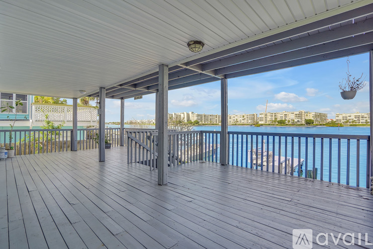 A wooden deck with a metal railing and a view of the water and buildings.