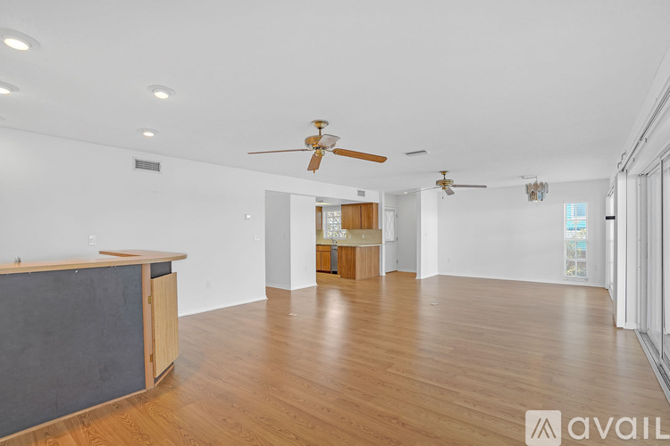 A spacious room with wooden floors and a ceiling fan.