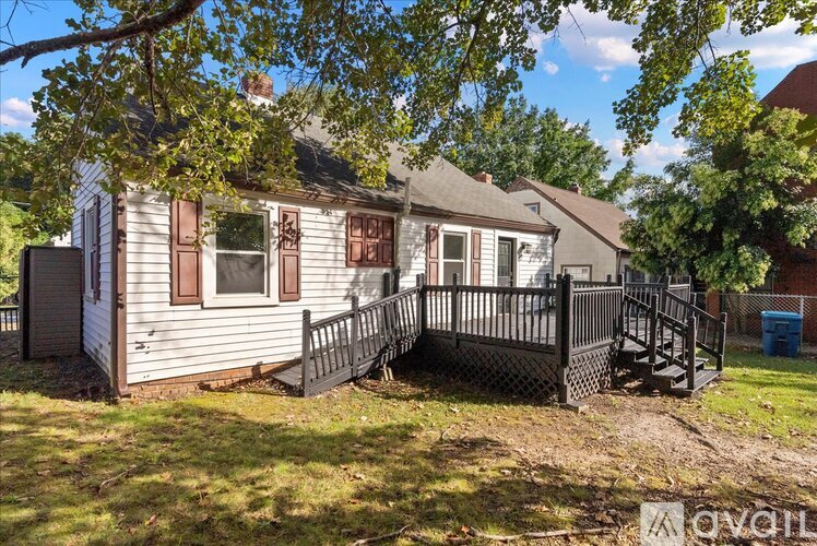 A house with a deck and a tree in front.