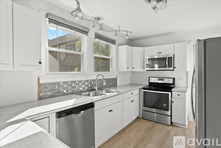 A modern kitchen with white cabinets and stainless steel appliances.