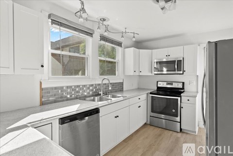 A modern kitchen with white cabinets and stainless steel appliances.