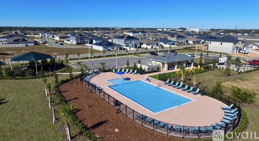 A swimming pool surrounded by a fence and a grassy area.