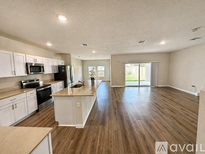A spacious kitchen with white cabinets and wooden flooring.