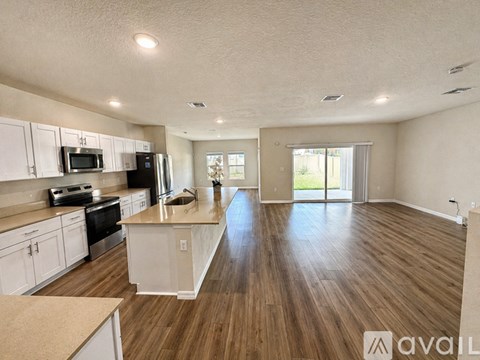 A spacious kitchen with white cabinets and wooden flooring.