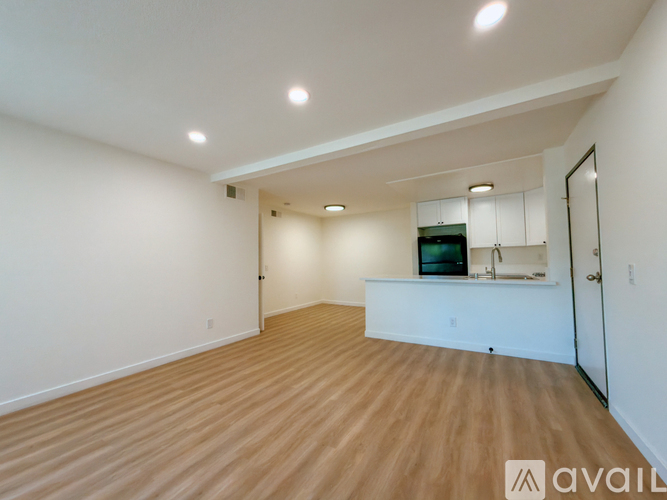 A spacious room with wooden flooring and a television in the corner.