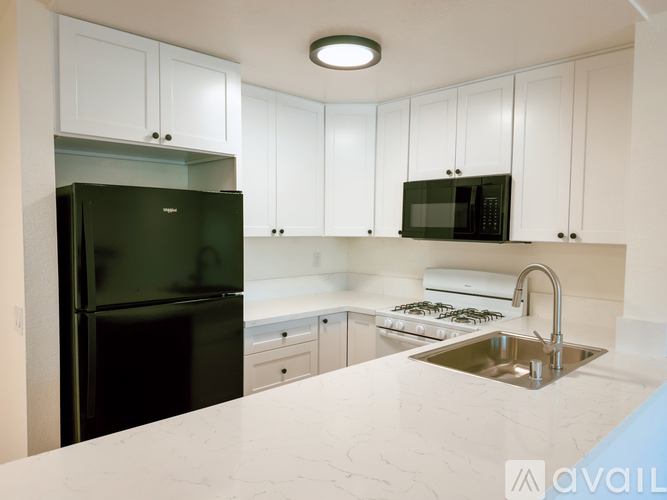 A kitchen with white cabinets and a black fridge.