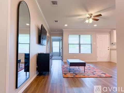 A spacious living room with a ceiling fan and a rug on the floor.