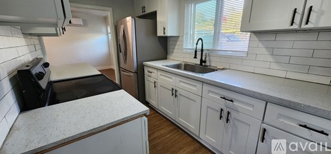 A kitchen with white cabinets and a black counter top.