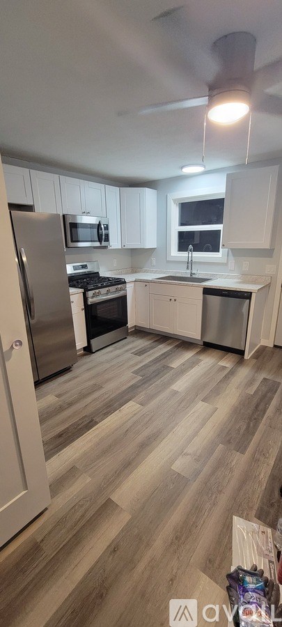A kitchen with white cabinets and a wooden floor.