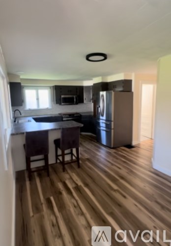 A kitchen with a wooden floor and a black fridge.