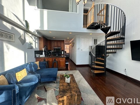 A living room with a blue couch and a spiral staircase.