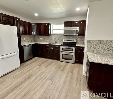 A kitchen with dark brown cabinets and a white refrigerator.