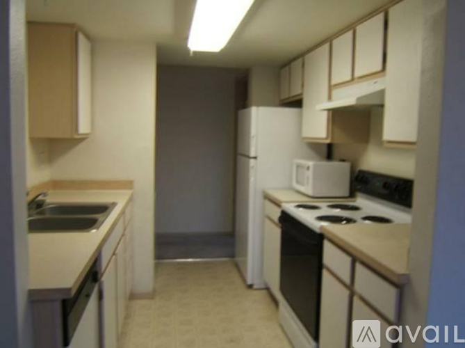 A kitchen with white appliances and beige cabinets.