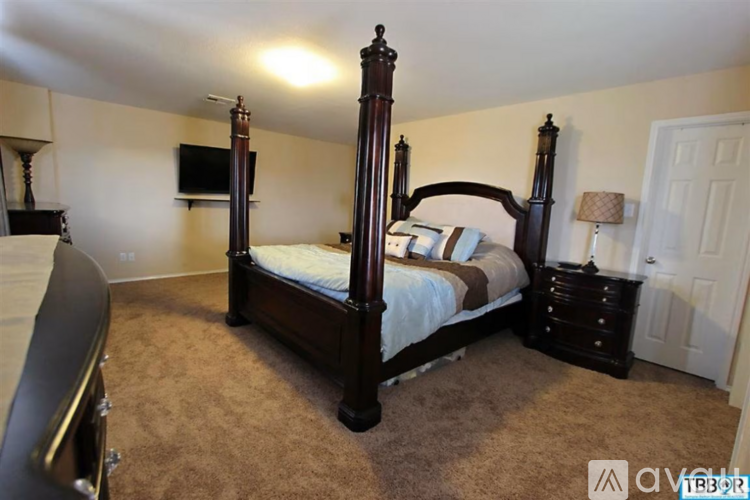 A bedroom with a four poster bed and a television on the wall.