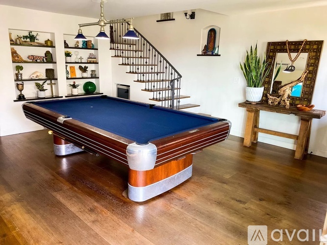 A pool table in a room with a staircase in the background.