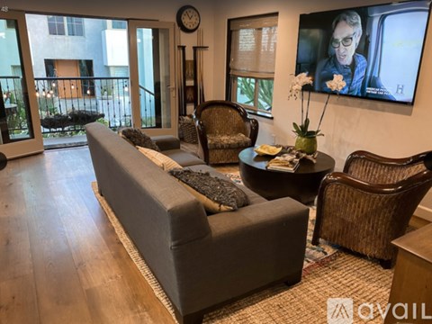 A living room with a grey couch, a brown chair, a coffee table, and a painting on the wall.