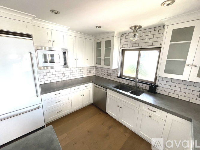 A kitchen with white cabinets and a black countertop.
