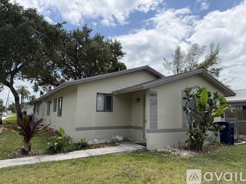 A beige house with a tree in front of it.