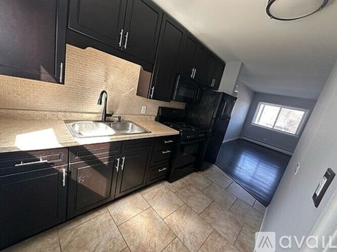 A kitchen with black cabinets and a tiled floor.