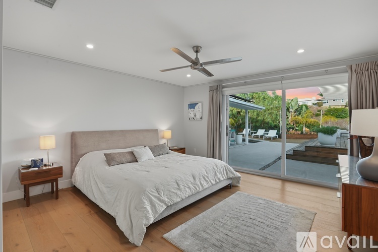A bedroom with a large bed and a sliding glass door leading to a balcony.